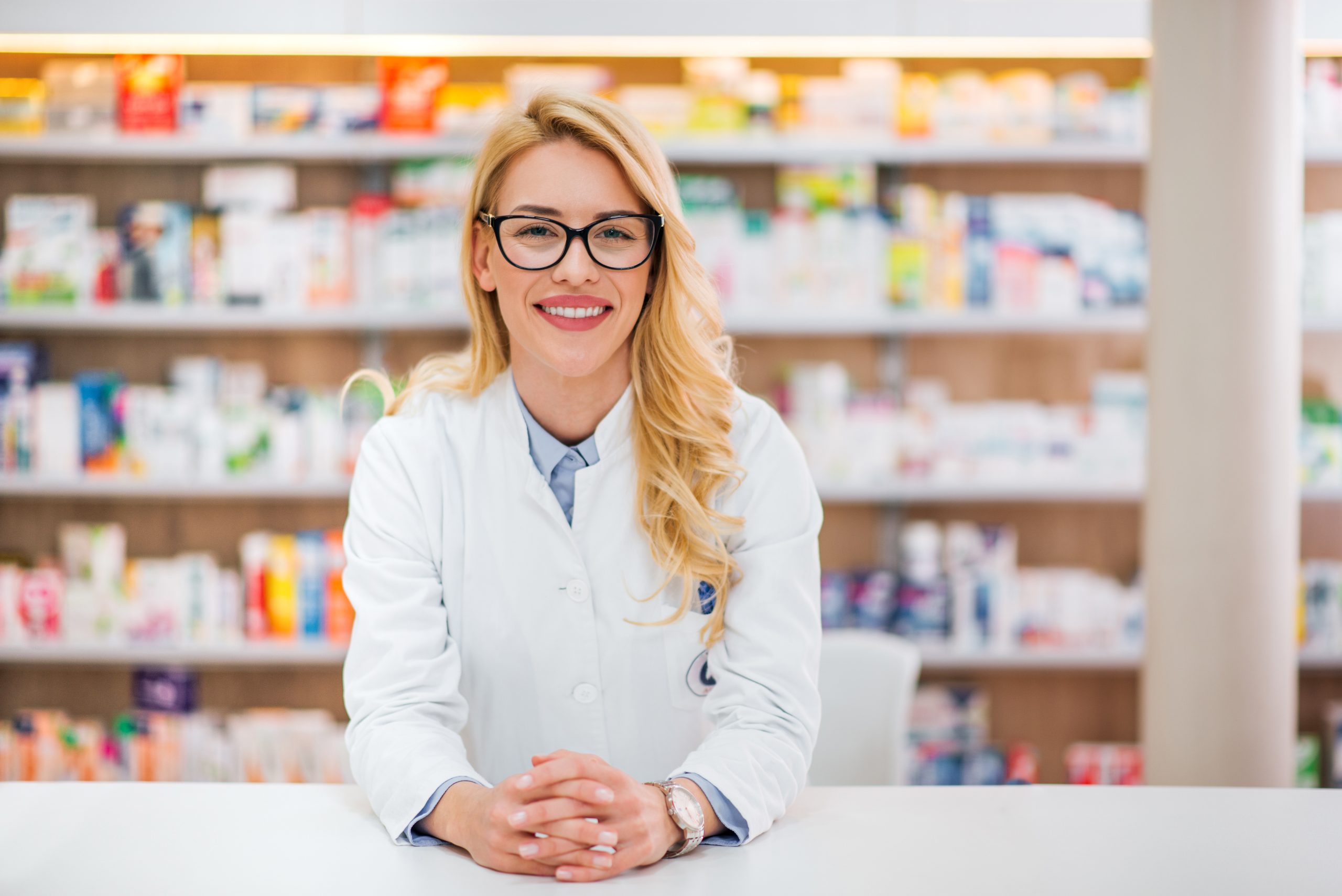 Portrait of a beautiful blonde pharmacist leaning on counter at